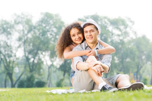 romantic couple lying on the grass in the summer park, spending time with loved ones