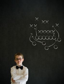 Thinking boy dressed up as business man with chalk American football strategy on blackboard background