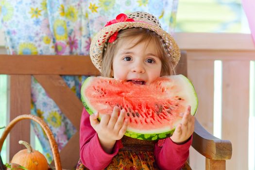 little girl in a straw hat with appetite eats a ripe water-melon