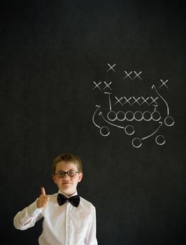 Thumbs up boy dressed up as business man with chalk American football strategy on blackboard background