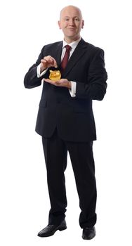 businessmandropping a pound into  a golden piggybank isolated on white