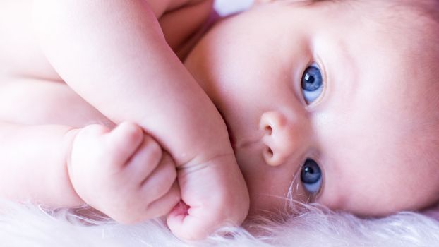 beautiful baby lying with light eyes lies, close-up
