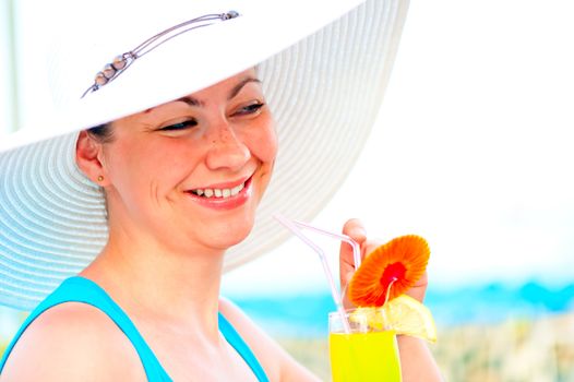 beautiful carefree girl in white hat with a cocktail in hand