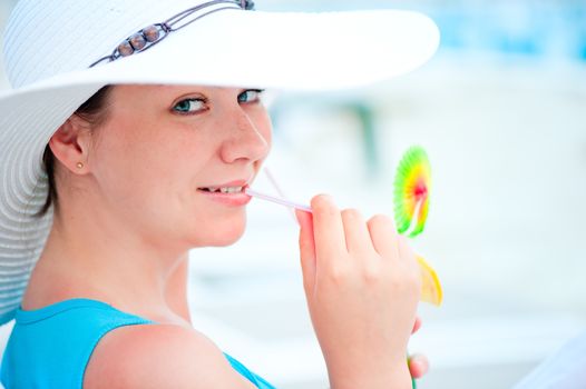 smiling woman in white hat drinking a cocktail