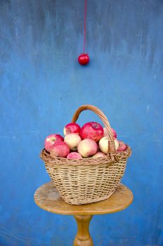 still-life with fresh apple basket on table and blue wall