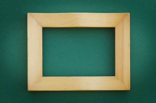 empty wooden picture frame hanging on a blank green wall