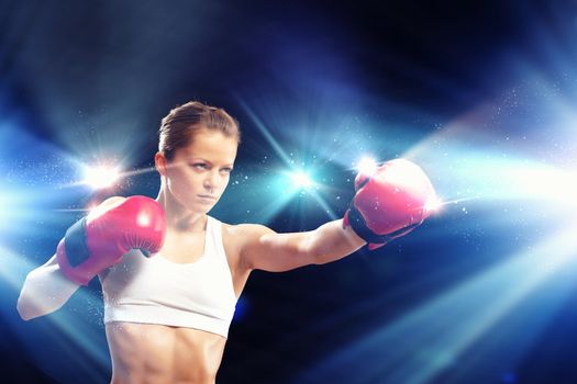 Young pretty boxer woman standing in light flashes
