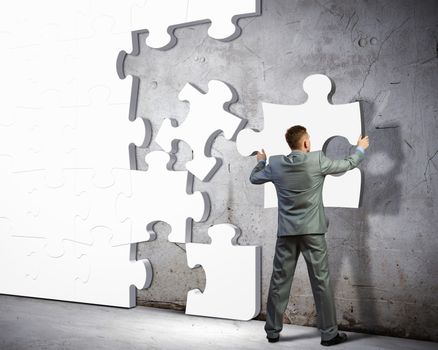 Image of businessman compiling macro white puzzle. Building business