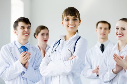 Attractive female doctor in uniform congratulated by colleagues