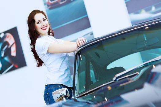 Pretty woman standing near car at car center. Choosing a car