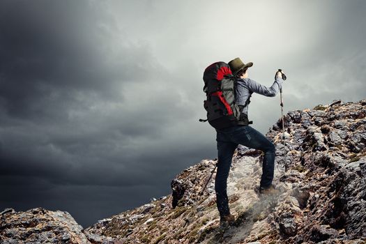 Image of young man mountaineer standing atop of rock