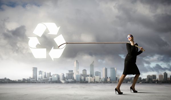 Image of businesswoman in goggles pulling recycle sign with rope