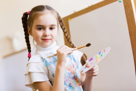 Little cute girl with paint brush and easel