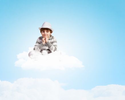 Image of little cute boy smiling sitting on clouds