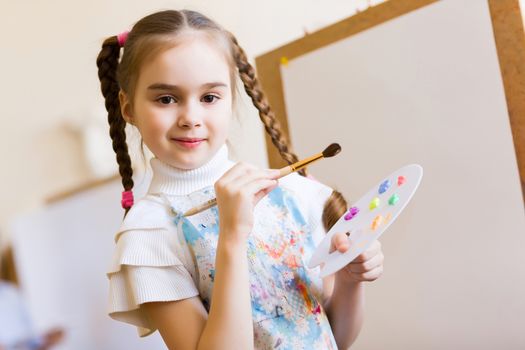 Little cute girl with paint brush and easel