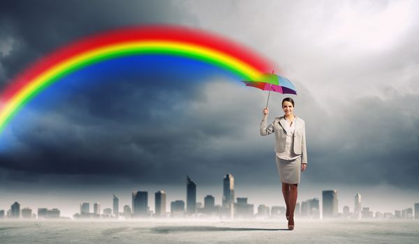 Young business woman in suit standing and holding an umbrella