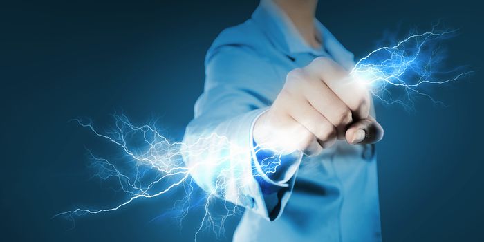 Image of powerful businesswoman holding lightning in fist