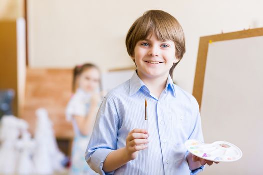 Image of little cute boy painting pictures at kindergarten