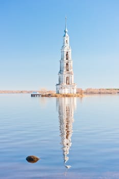 High belltower in the middle of the wide river