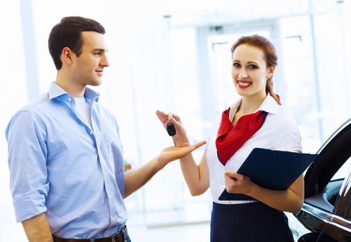 Young man choosing car at salon with help of consultant