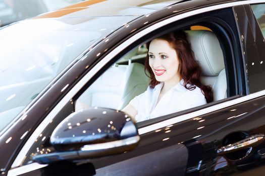 Attractive young woman sitting in car in car center