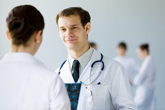 Young doctor in white uniform talking to colleague