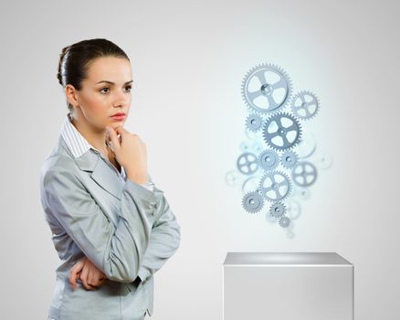Image of thoughtful businesswoman looking at gears. Business structure