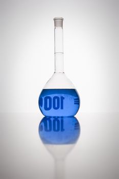 A glass bottle with blue liquid in a laboratory