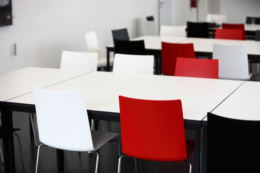 Empty red and white tables and chairs in a cafeteria or venue for eating a meal or holding a meeting