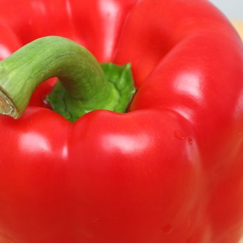 Close-up of a fresh shiny nutritive red bell pepper with a green stem