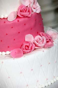 Tiered wedding cake decorated with pink roses made of icing sugar to match the pink and white alternating tiers