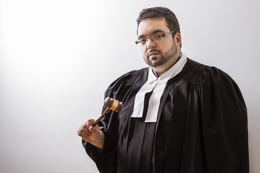 Overweight man in canadian lawyer toga, with a gavel in his hand