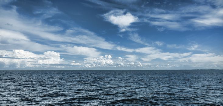 Blue horizon between the ocean and beautiful blue cloudy sky.