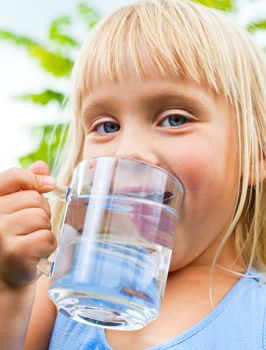 Cute little girl drinking water outdoors