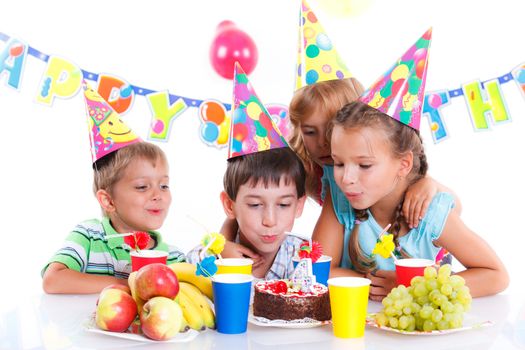 Group of adorable kids having fun at birthday party with birthday cake