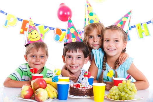 Group of adorable kids having fun at birthday party with birthday cake