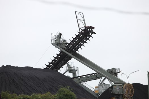 Open cast mining for crushed stone for use in the construction industry with large conveyor belts pouring processed stone onto heaps