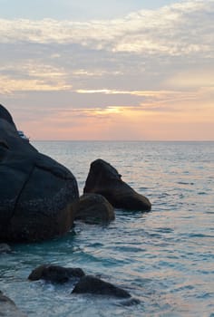 Big stones on an ocean coast against a sunset in tropics, Thailand