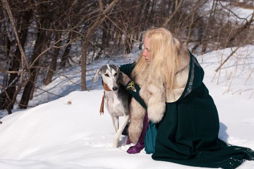 A blonde girl and a grey saluki on snow
