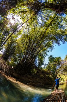 Wide angle view of Black man steering bamboo boat