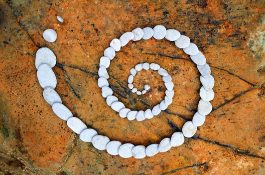 Spiral of pebbles on the sea boulder