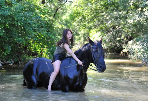 young woman and her black stallion in a river