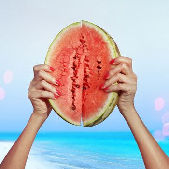 two pieces of ripe water-melon in hands, beach