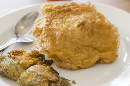 fried fish and omelet in dish with spoon and fork