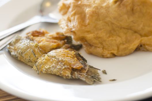 fried fish and omelet in dish with spoon and fork