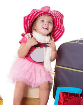 Happy baby girl with glasses, hat and suitcase isolated on white
