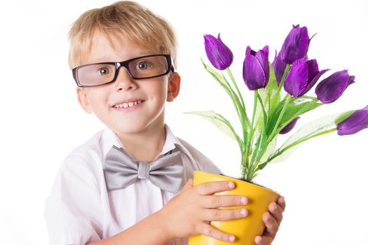 Smiling boy in glasses and bow-tie with flowers over white