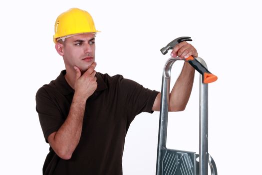 Doubtful man holding a hammer and a ladder