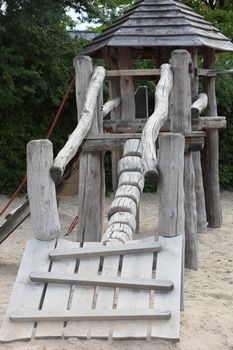 Rustic wooden playground equipment in the form of a challenging ramp leading up to a small hexagonal hut