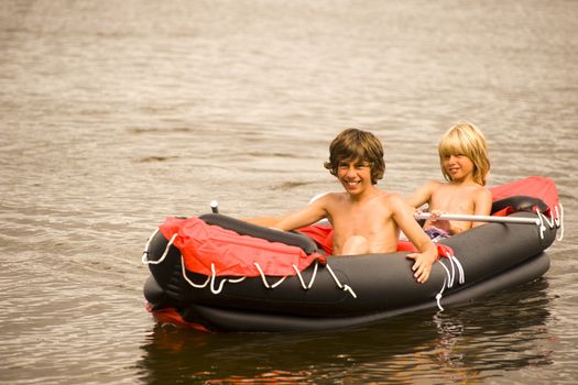 two boys in a rubber boat at the lake